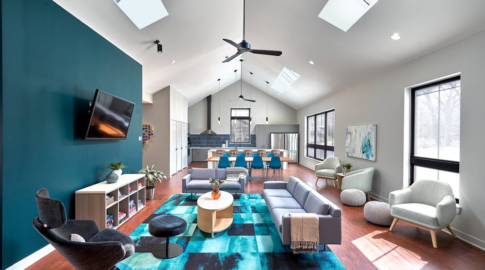 The design turned a formerly dark, dingy living room into a large, open, light-filled space thanks to the expansive windows and skylights, with rich, deep teal accents that extend from the great room to the kitchen beyond.