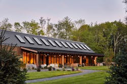 An exterior view of the AutoCamp Catskills location showcases the two adjoining barns nestled within the forest.