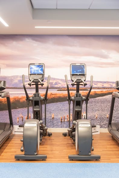 The fitness center features a floor to ceiling image of Mission Bay.