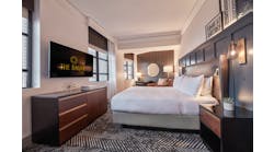 HBA Los Angeles renovated The Dagny Boston Hotel with guest rooms featuring wainscoting accents in handsome blue. This superior king room has build-in reading lights and woven and leather-like fabric wraps on the furniture.