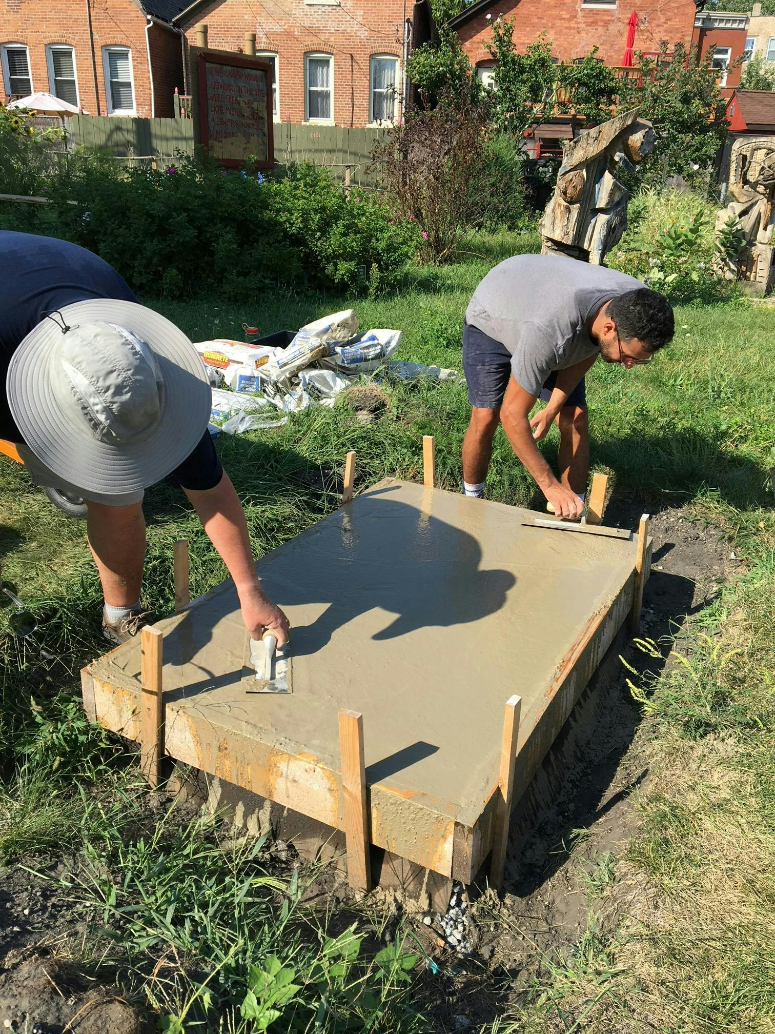 Garden leaders Robert Kempa and Cain Baum pour new plinth base to facilitate water drainage away from sculpture.