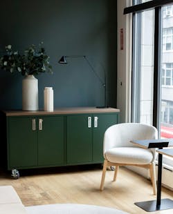 Individual lounge chair with computer table on wood flooring with storage cabinet next to window. Individual lounge chair with computer table on wood flooring with storage cabinet next to window.