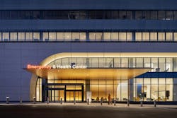 Nightime exterior view of emergency room entrance with glass facade and warm lighting. Nightime exterior view of emergency room entrance with glass facade and warm lighting.