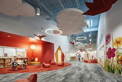 Bright, colorful hallway in elementary school with floral wall prints, an orange reading nook, and birds and cloud sculptures hanging from ceiling. Bright, colorful hallway in elementary school with floral wall prints, an orange reading nook, and birds and cloud sculptures hanging from ceiling.