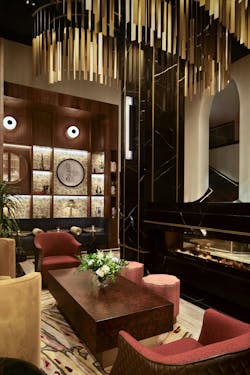 Lounge seating area in hotel lobby with dark wood coffee table and paneling, and gold-metallic ceiling fixture. Lounge seating area in hotel lobby with dark wood coffee table and paneling, and gold-metallic ceiling fixture.