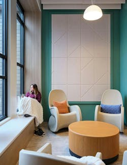 Quiet, comfortable seating area with rocking chairs, acoustic wall panels, and woman sitting by window with blanket. Quiet, comfortable seating area with rocking chairs, acoustic wall panels, and woman sitting by window with blanket.