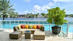 Outdoor upholstered sofa with pillows in front of swimming pool in a tropical environment. Outdoor upholstered sofa with pillows in front of swimming pool in a tropical environment.