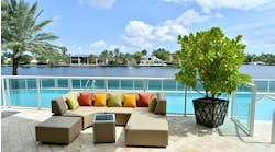 Outdoor upholstered sofa with pillows in front of swimming pool in a tropical environment. Outdoor upholstered sofa with pillows in front of swimming pool in a tropical environment.