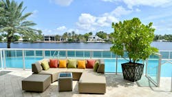 Outdoor upholstered sofa with pillows in front of swimming pool in a tropical environment. Outdoor upholstered sofa with pillows in front of swimming pool in a tropical environment.