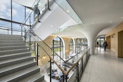 View of staircase from second floor with glass windows overlooking student lounge below. View of staircase from second floor with glass windows overlooking student lounge below.