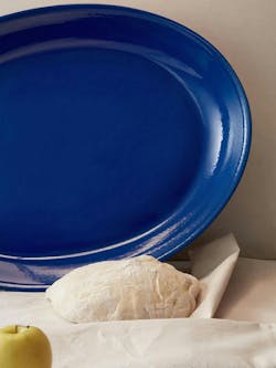 The Paris Platter in blue propped up against a wall with dough and an apple. The Paris Platter in blue propped up against a wall with dough and an apple.