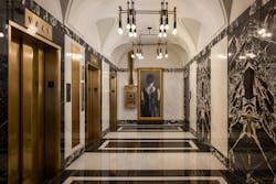 Historic veined marble wall slabs and deep brass-colored elevator doors preserve the historic Midland Lofts building lobby's deco aesthetic. Historic veined marble wall slabs and deep brass-colored elevator doors preserve the historic Midland Lofts building lobby's deco aesthetic.