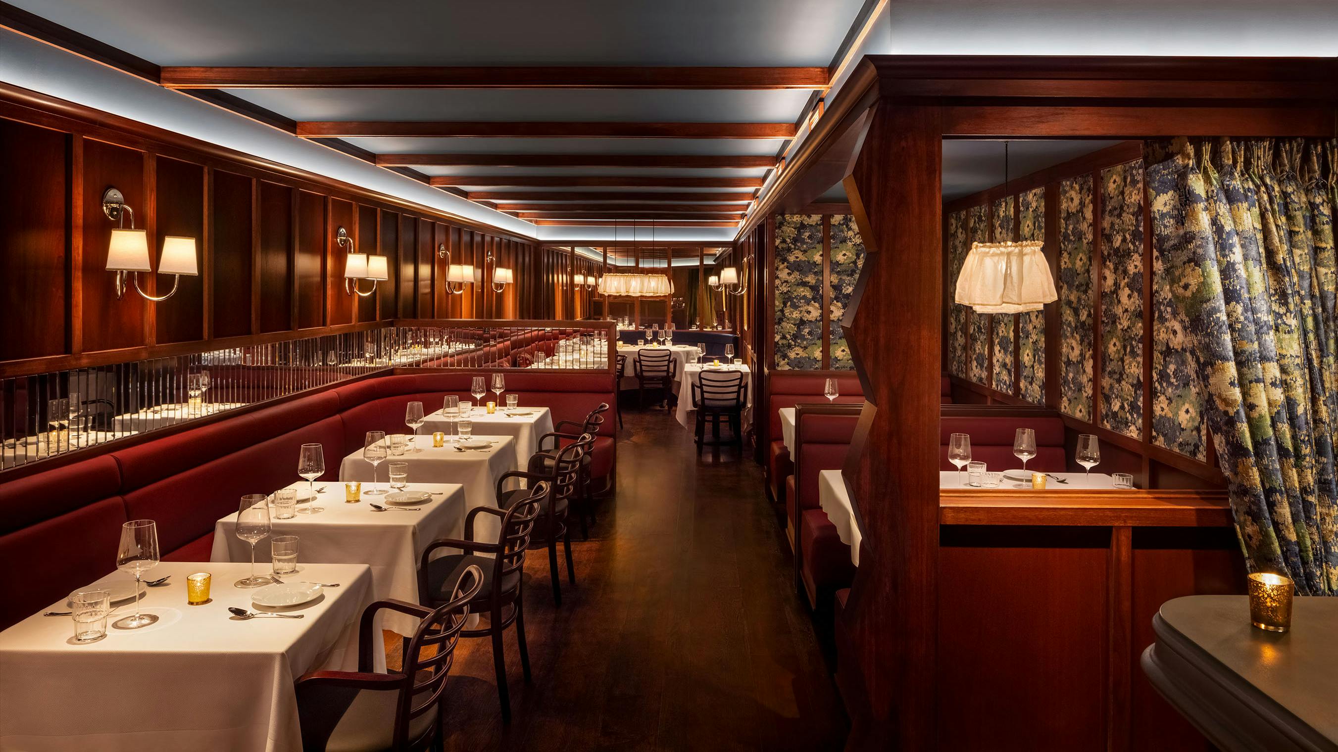The dining room at Chez Fifi in New York City features luxurious mahogany paneling and soft, indirect lighting that maintains a cozy atmosphere.