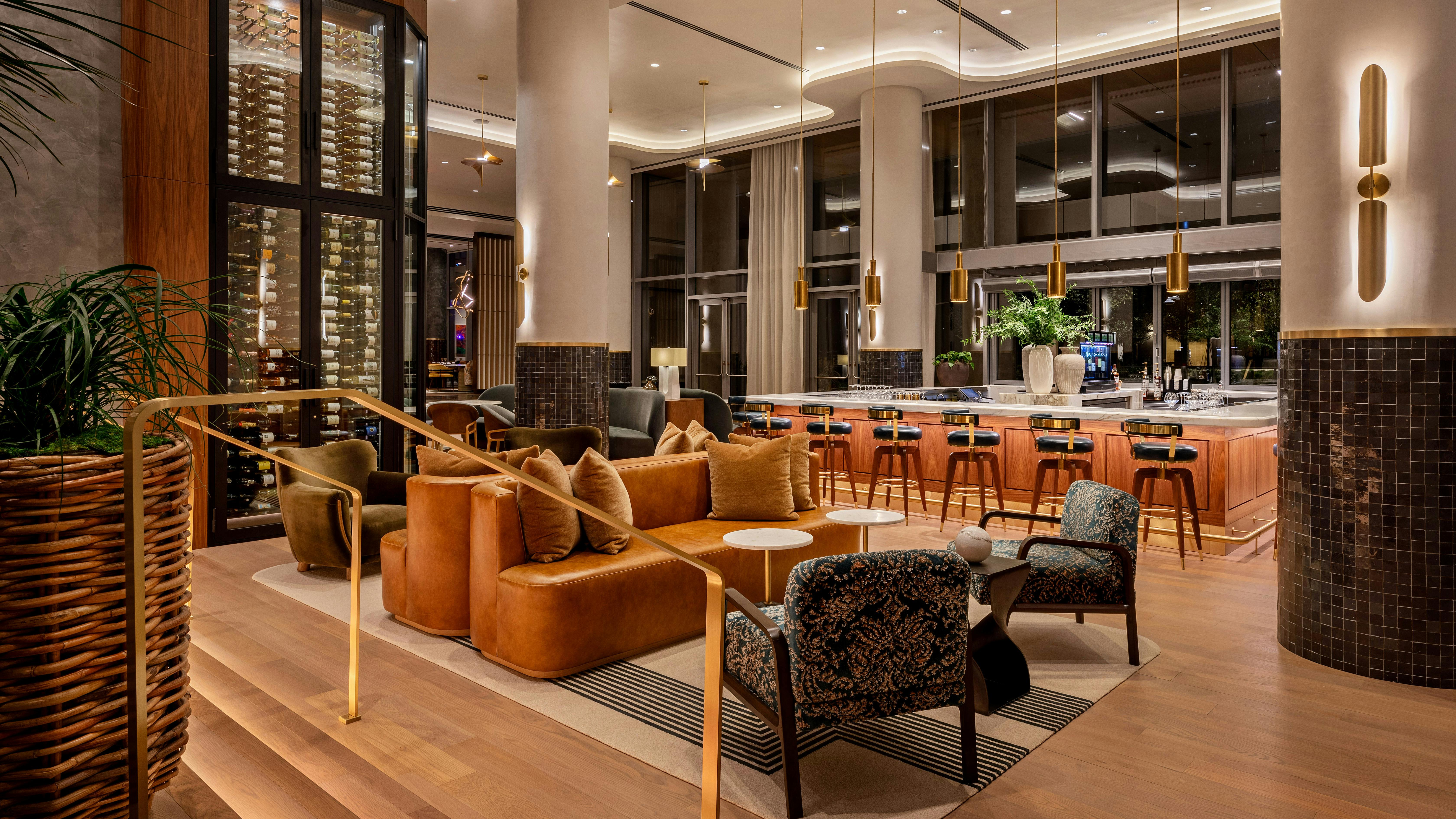 Layered pendant, wall, recessed ceiling, and hidden cove lighting accentuate the glossy sheen of tile surfaces, the glow of burnished metals, and the satin finish of natural woods in the Palato Wine Lounge.