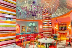 Brightly colored dining area with multi-colored glass tiles, chandeliers, and chairs. Brightly colored dining area with multi-colored glass tiles, chandeliers, and chairs.