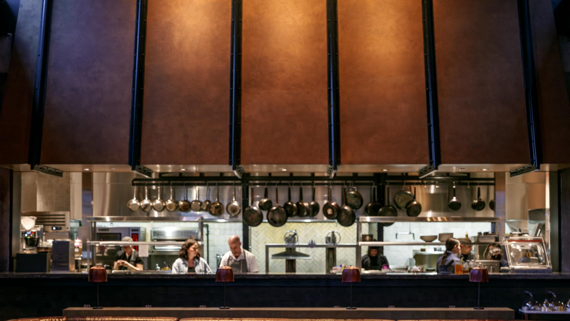 Amelia Gene's open kitchen with large, industrial looking cooper hood faces the main restaurant seating