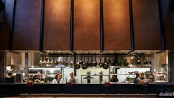 Amelia Gene's open kitchen with large, industrial looking cooper hood faces the main restaurant seating Amelia Gene's open kitchen with large, industrial looking cooper hood faces the main restaurant seating