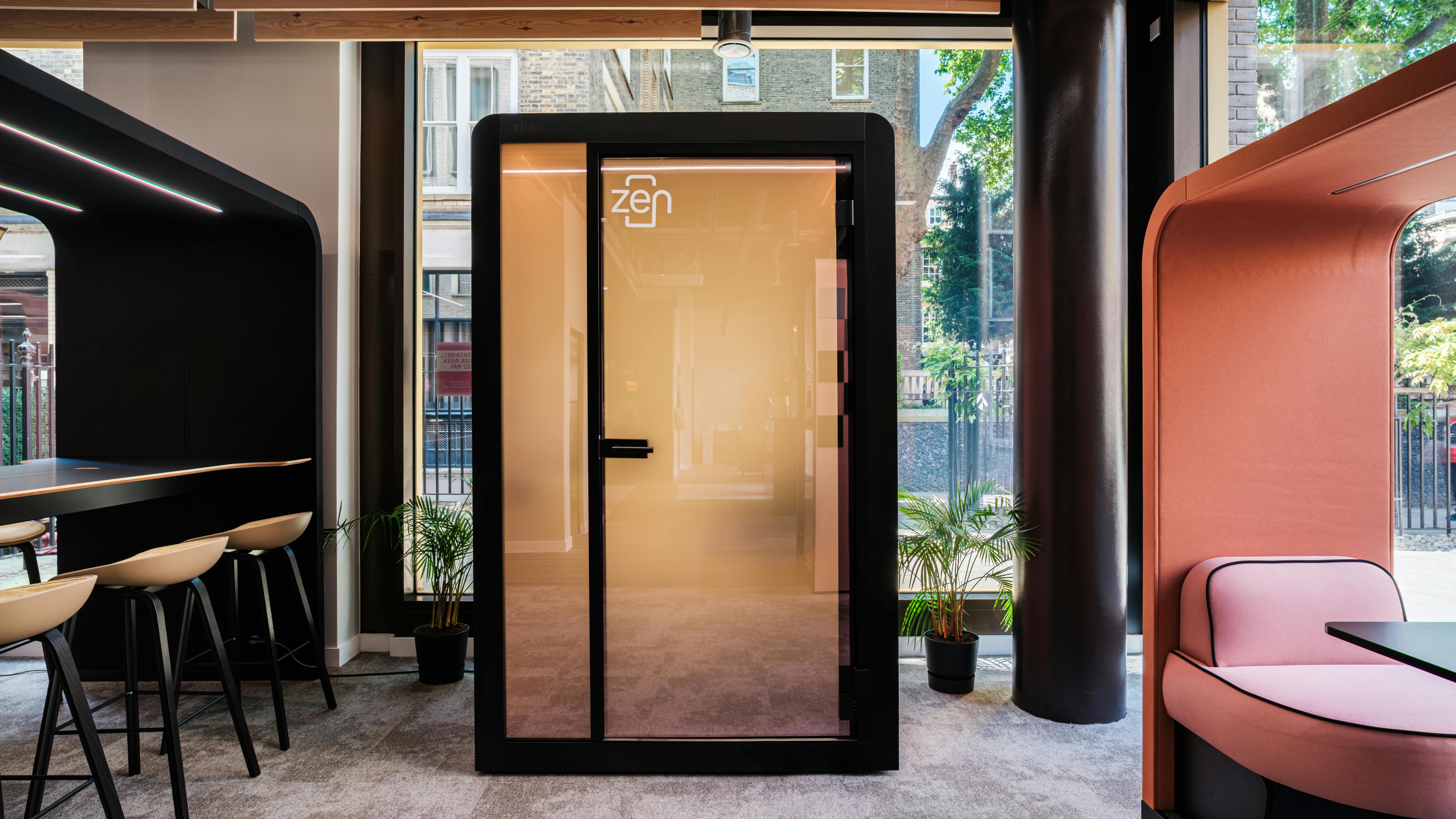 Privacy pod with frosted glass door in modern office interior space.