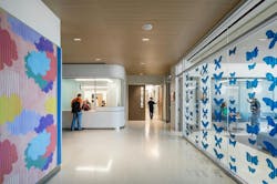 Corridor in children's unit with vibrant colored clouds on one wall and blue butterflies printed on glass divider Corridor in children's unit with vibrant colored clouds on one wall and blue butterflies printed on glass divider