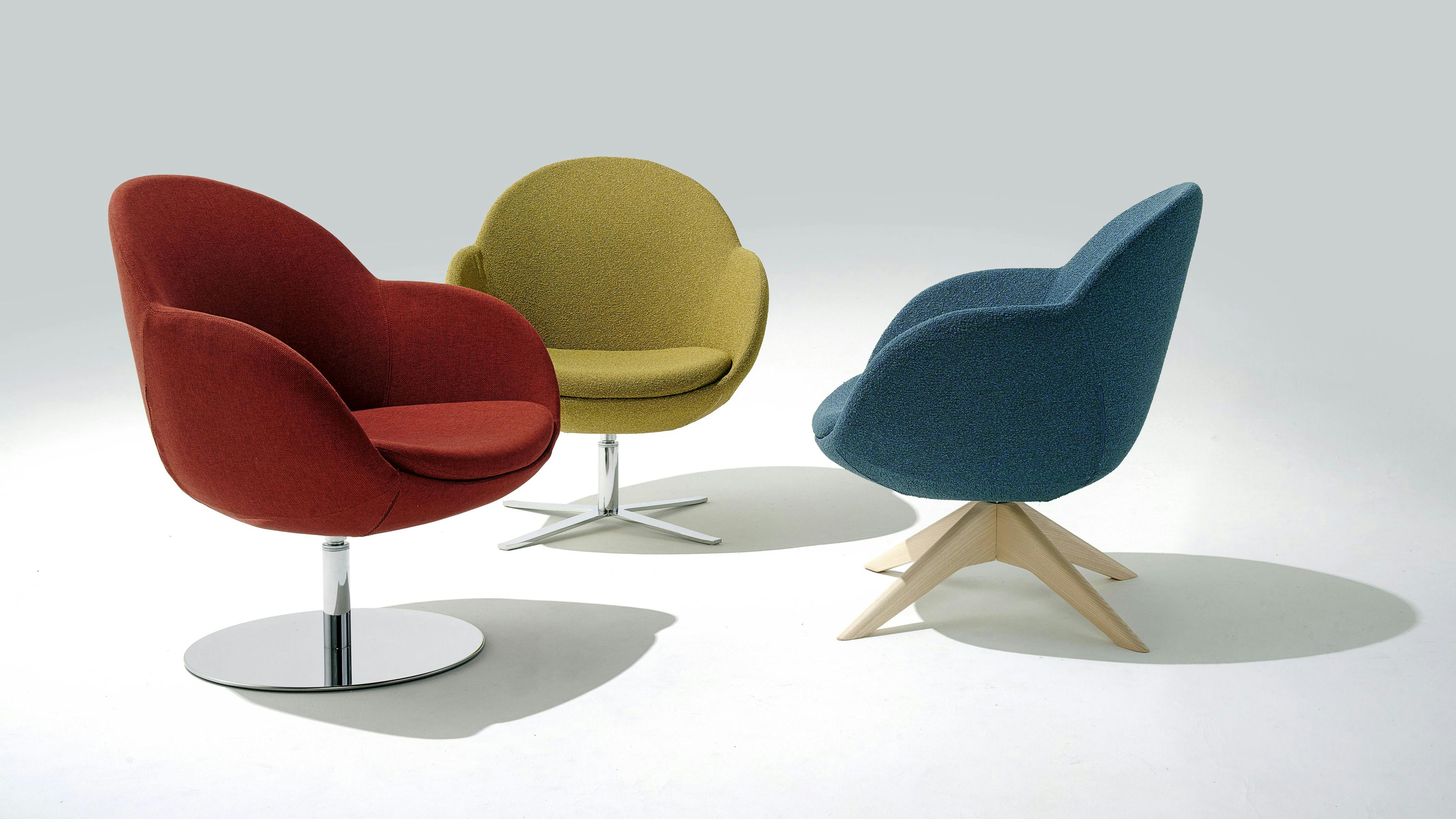 Three modern upholstered lounge chairs in three colors with wood and metal bases.
