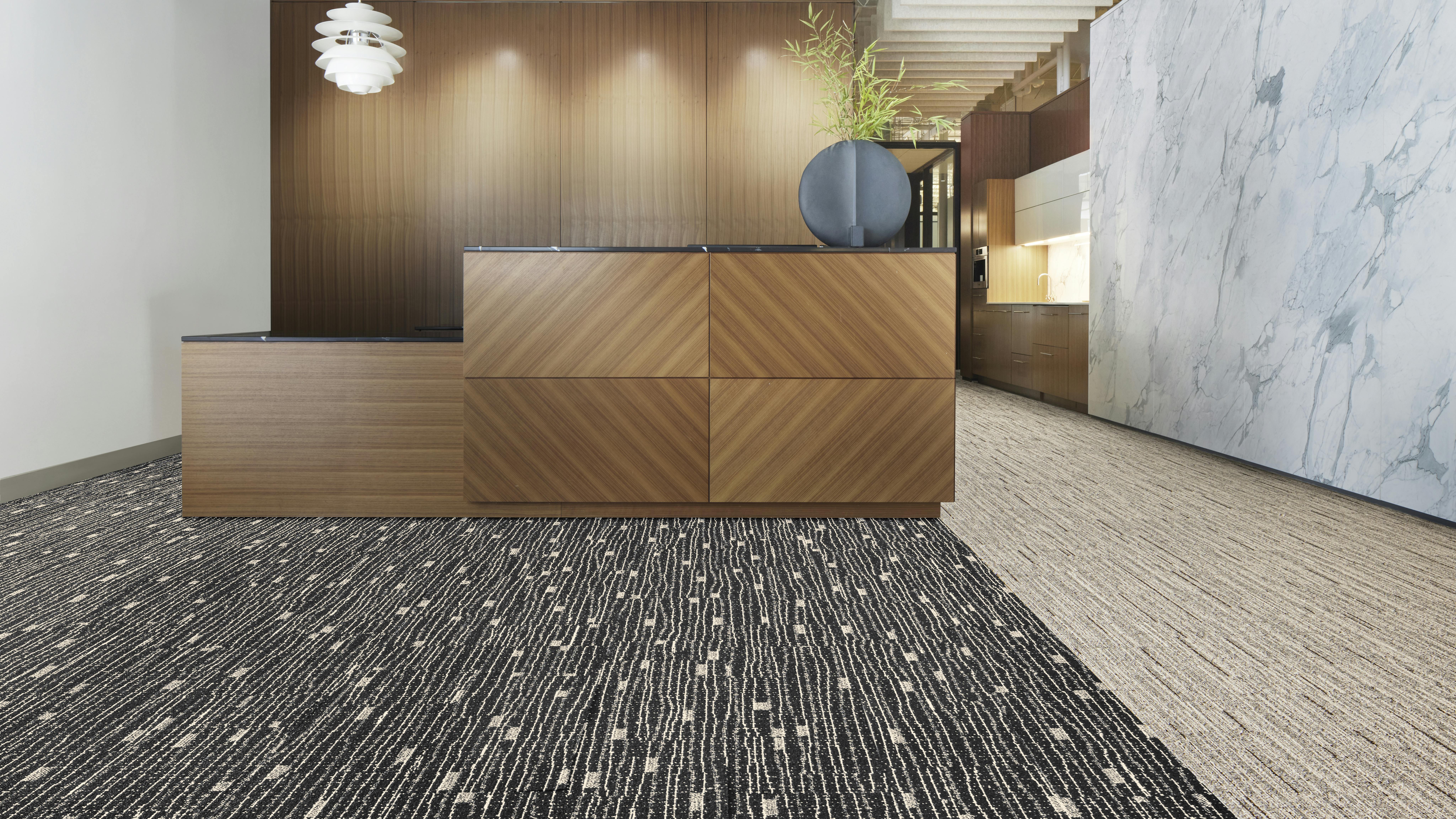 Close up of carpet with inverse cream and black colors in an office setting in front of a wood reception desk.