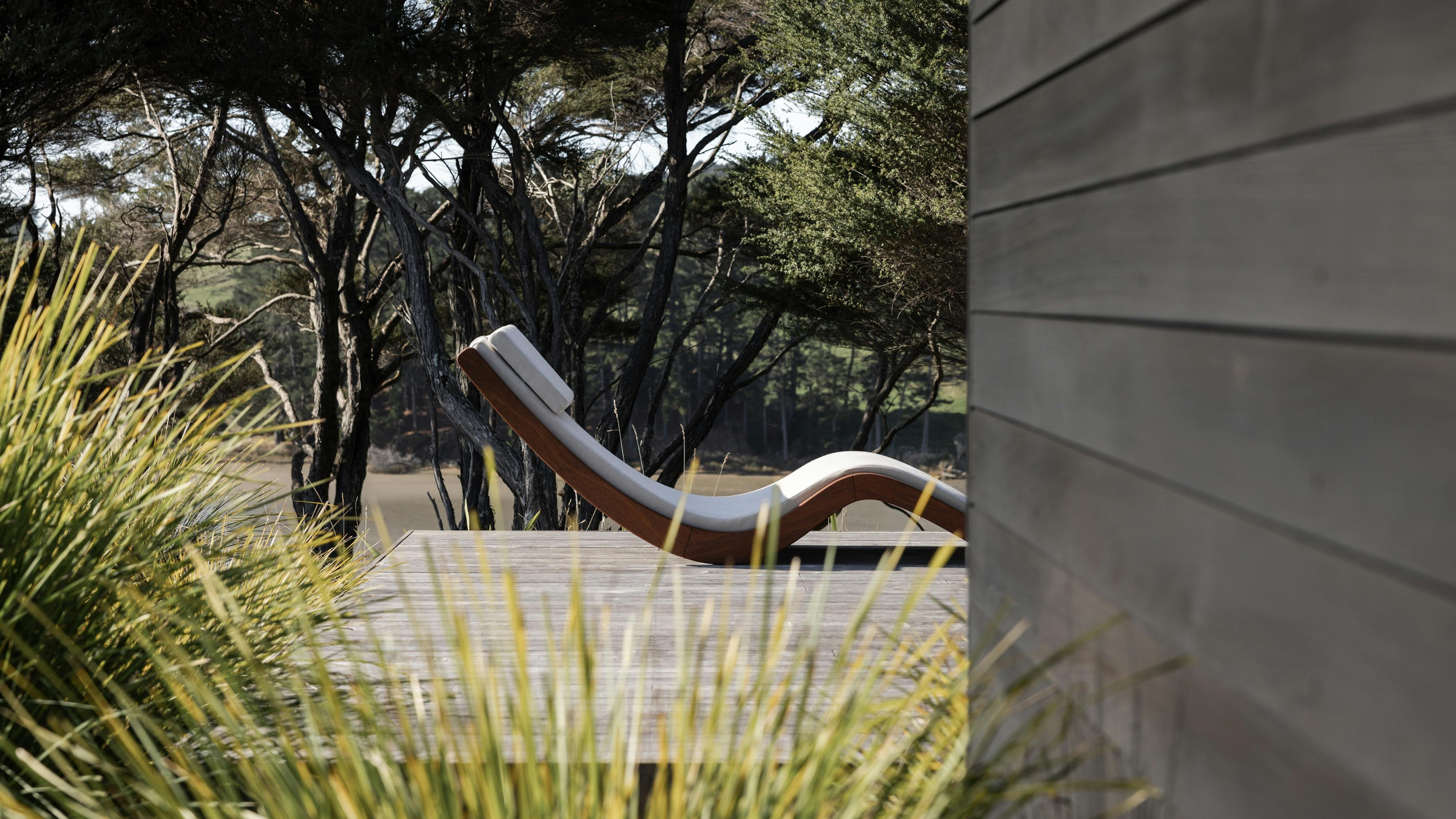 The Ko Lanta Sun Lounger offers multiple reclining options, perfect for outdoor relaxation. The lounger is shown on an outdoor patio surrounded by trees and shrubs.