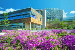 Phipps Conservatory Center for Sustainable Landscapes main building exterior with wood facade, and steel and glass building behind, with purple flowering native plants in the foreground. Phipps Conservatory Center for Sustainable Landscapes main building exterior with wood facade, and steel and glass building behind, with purple flowering native plants in the foreground.