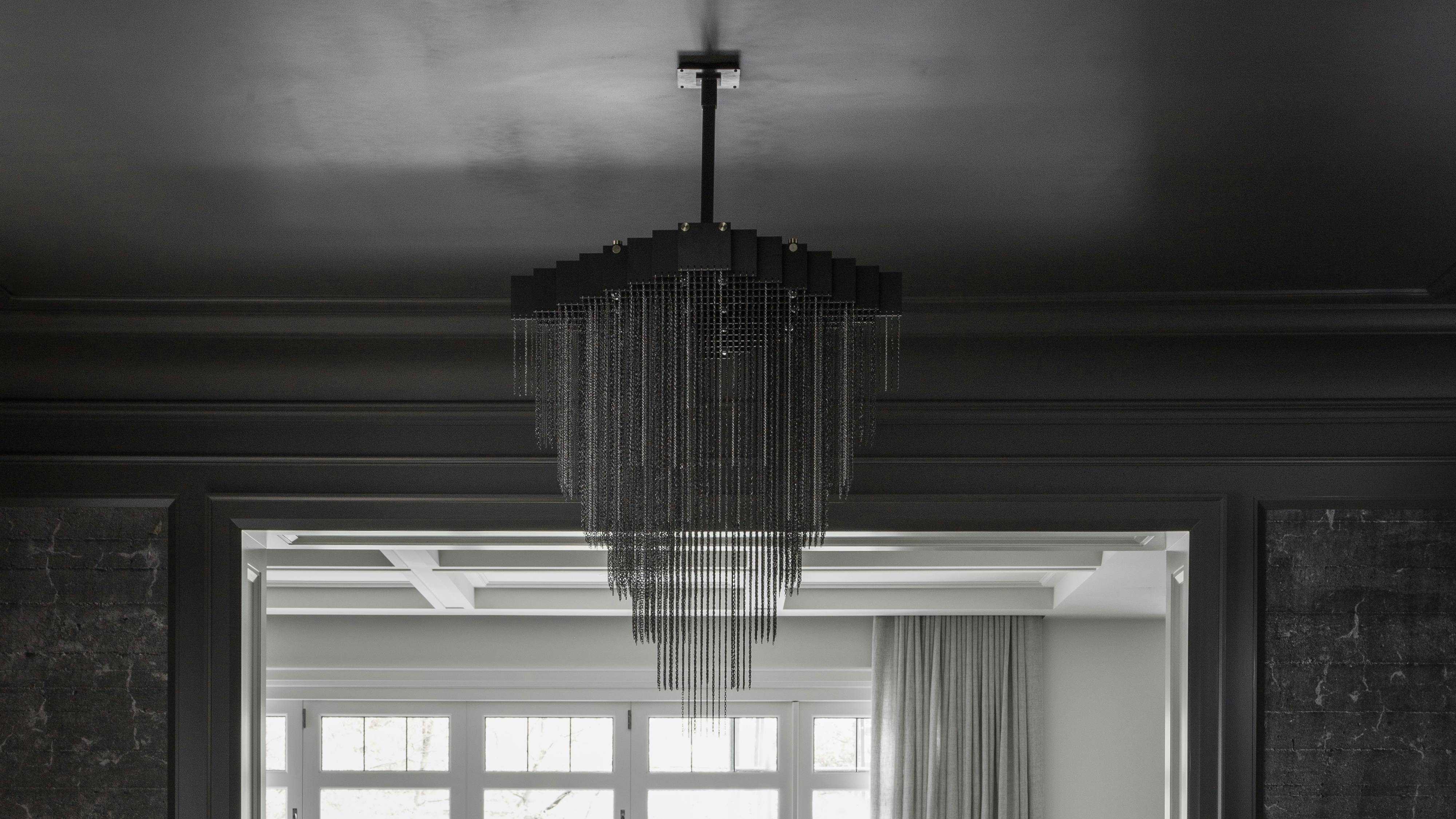 Kelly Chandelier X-Large in black from Gabriel Scott suspended over a table.