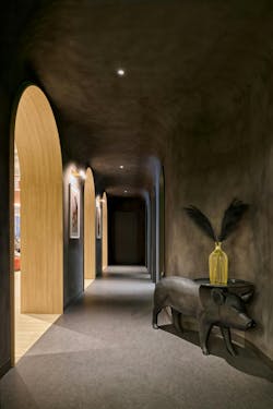 Dimly lit arched hallway with a small gilded pig accent table in the foreground. Dimly lit arched hallway with a small gilded pig accent table in the foreground.