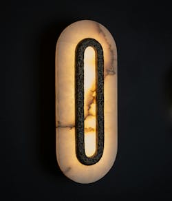 Omero combines brass, glass, and shadow to create an atmospheric glow. A close-up of the light is shown. Omero combines brass, glass, and shadow to create an atmospheric glow. A close-up of the light is shown.