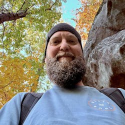 Market Content Director Robert Nieminen stands in a wooded hiking area on a fall day Market Content Director Robert Nieminen stands in a wooded hiking area on a fall day