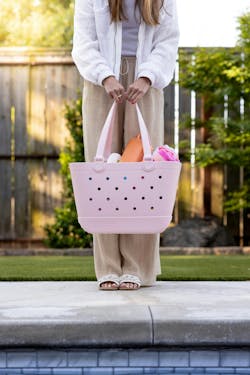 A woman is shown holding the Getaway Bag at poolside. A woman is shown holding the Getaway Bag at poolside.