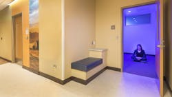 Quiet room in healthcare facility with woman seated in a meditation pose on the floor Quiet room in healthcare facility with woman seated in a meditation pose on the floor