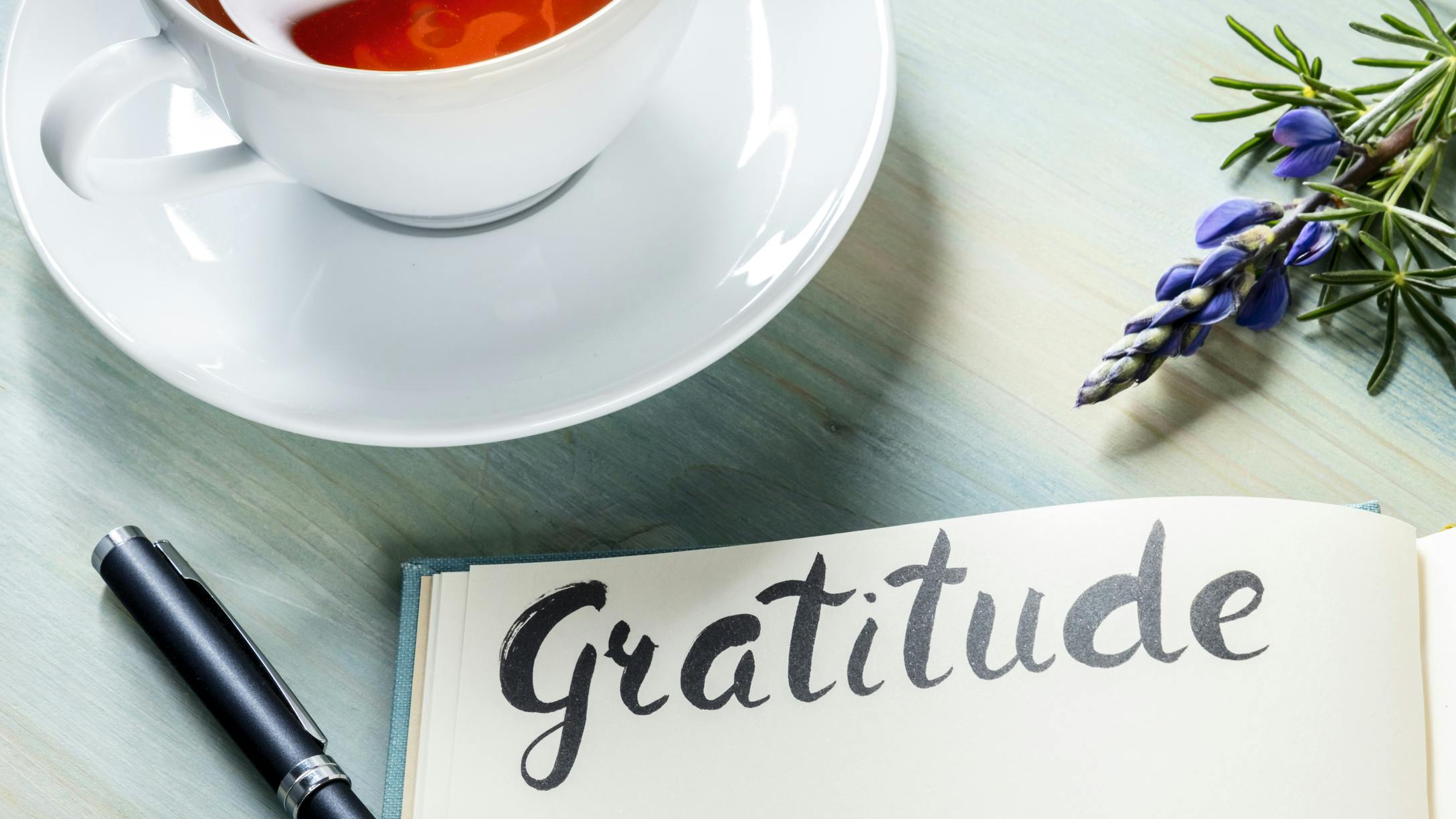 A gratitude journal with teacup and spring of lavender plant