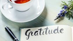 A gratitude journal with teacup and spring of lavender plant A gratitude journal with teacup and spring of lavender plant