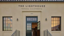 Exterior view of The Lighthouse entrance with light tan stucco facade and black exterior roof and window detailing. Exterior view of The Lighthouse entrance with light tan stucco facade and black exterior roof and window detailing.