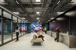 Long view photo of Dreamwall digital display in open gathering area, with glass walls on corridor and modern black gridded ceiling treatment. Long view photo of Dreamwall digital display in open gathering area, with glass walls on corridor and modern black gridded ceiling treatment.