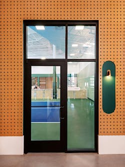 Entrance to pickleball court features pegboard paneling. Entrance to pickleball court features pegboard paneling.