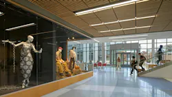 Hallway with glass wall showing fashion mannequins in foreground with staircase and glass wall with students walking in background. Hallway with glass wall showing fashion mannequins in foreground with staircase and glass wall with students walking in background.