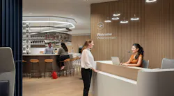 Woman standing at reception desk at the Lufthansa airlines lounge talking to receptionist with bar area in the background. Woman standing at reception desk at the Lufthansa airlines lounge talking to receptionist with bar area in the background.