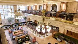 A second-floor view of the Banking Hall, which features high decorative ceilings, marble, and bold material choices, complemented by restrained wood and brass design features. A second-floor view of the Banking Hall, which features high decorative ceilings, marble, and bold material choices, complemented by restrained wood and brass design features.