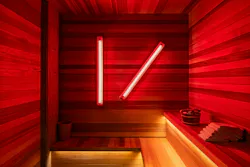 A repurposed sauna with wood paneling and diffused linear red lights leads guests to the exclusive Naisho Room speakeasy. A repurposed sauna with wood paneling and diffused linear red lights leads guests to the exclusive Naisho Room speakeasy.