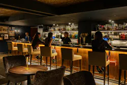 None of the Above speakeasy at STL bar with under-counter lighting, dark tiled ceilings and wood furnishings, and splashes of refined gold decor and upholstered seating., None of the Above speakeasy at STL bar with under-counter lighting, dark tiled ceilings and wood furnishings, and splashes of refined gold decor and upholstered seating.,