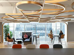 Casual seating area in workplace with a variety of seating heights with people gathered and geometric ceiling pattern. Casual seating area in workplace with a variety of seating heights with people gathered and geometric ceiling pattern.