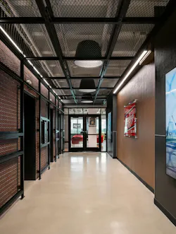 In the corporate workspace, brick walls and ceiling ductwork are layered with metal industrial mesh similar to the stairway and balcony in the retail environment. In the corporate workspace, brick walls and ceiling ductwork are layered with metal industrial mesh similar to the stairway and balcony in the retail environment.