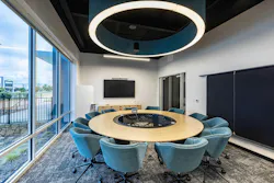 Windowed Dude Perfect conference room with round table in light neutral wood tone and coordinated seating and acoustic lighting in brand aqua Windowed Dude Perfect conference room with round table in light neutral wood tone and coordinated seating and acoustic lighting in brand aqua