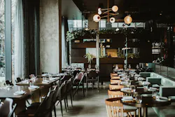 Restaurant interior featuring wide windows, cafe style tables, and banquettes with globe-shaped pendant style lighting overhead Restaurant interior featuring wide windows, cafe style tables, and banquettes with globe-shaped pendant style lighting overhead