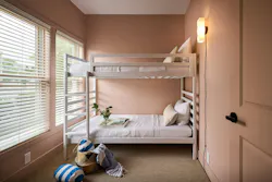 A dual-occupancy aparthotel room containing bunk beds layered with crisp white linens, and soft blush peach color drenched walls. A dual-occupancy aparthotel room containing bunk beds layered with crisp white linens, and soft blush peach color drenched walls.