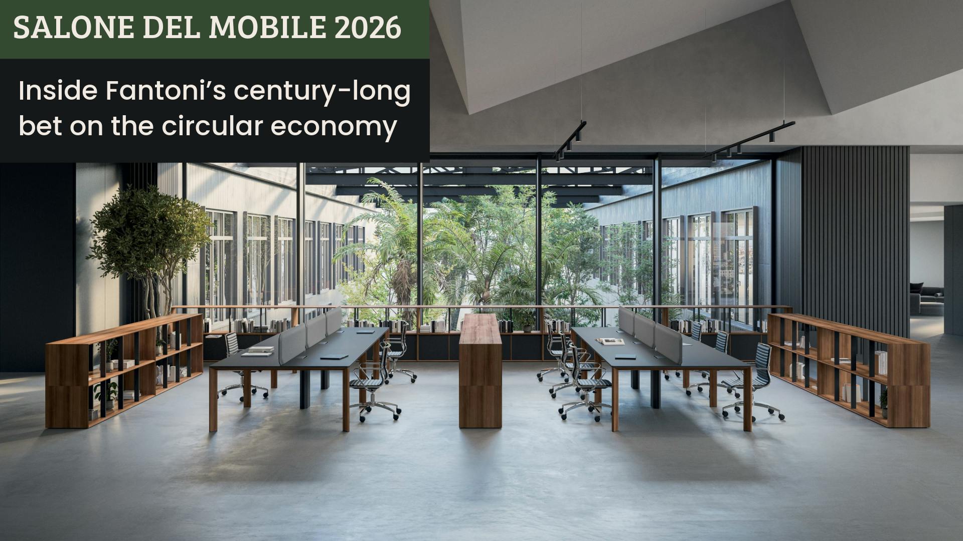 An open workspace has wood-look laminate shelves acting as dividers between long worktables with a window to interior courtyard