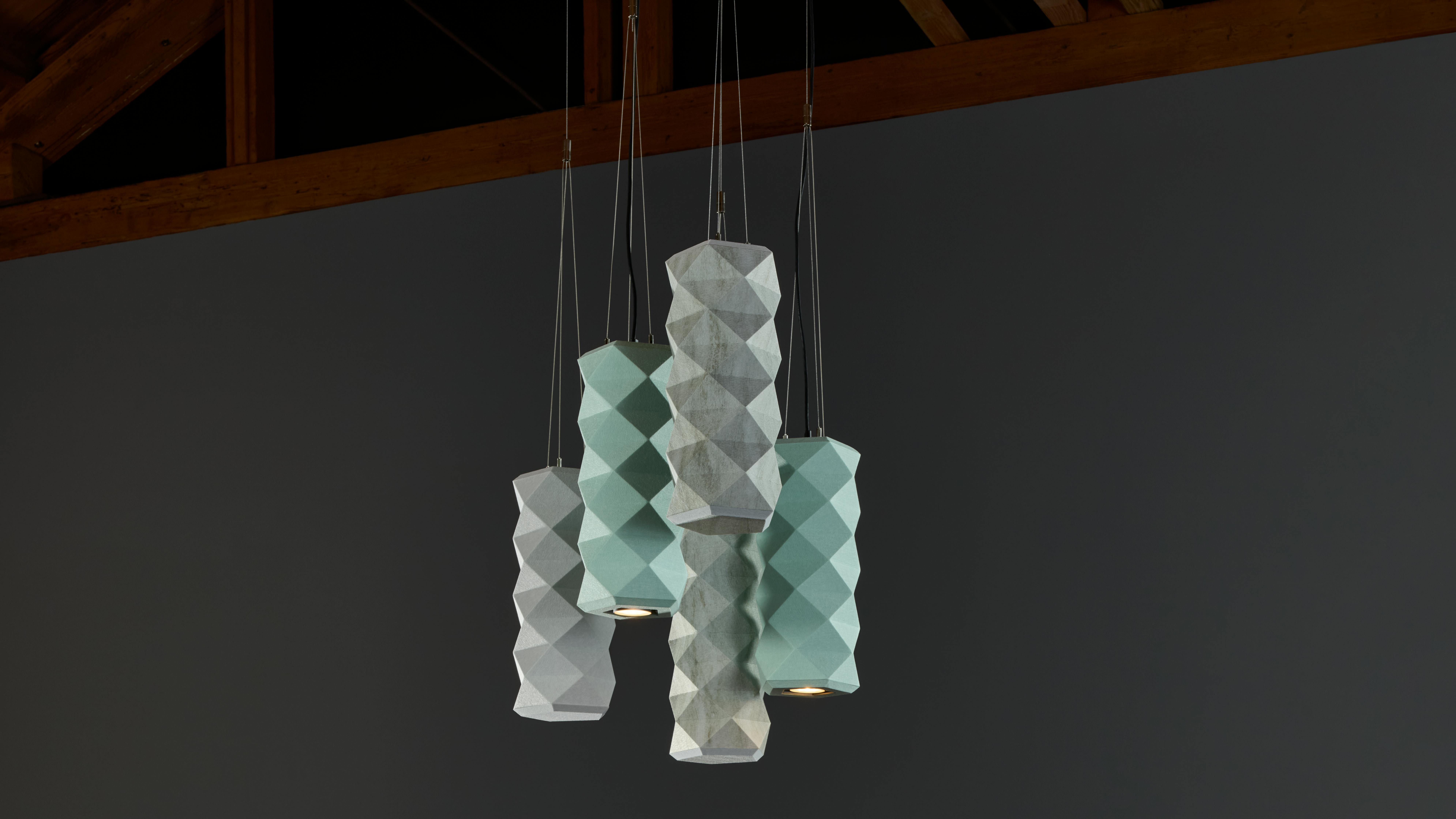 The Tessellate Pendant specified with integrated lighting offers flexible compositions in over 40 color options. Shows in teal and gray colors.